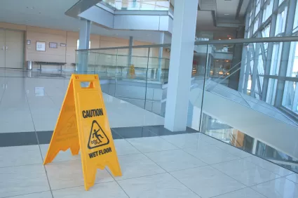 yellow caution sign standing up on a wet tile floor 